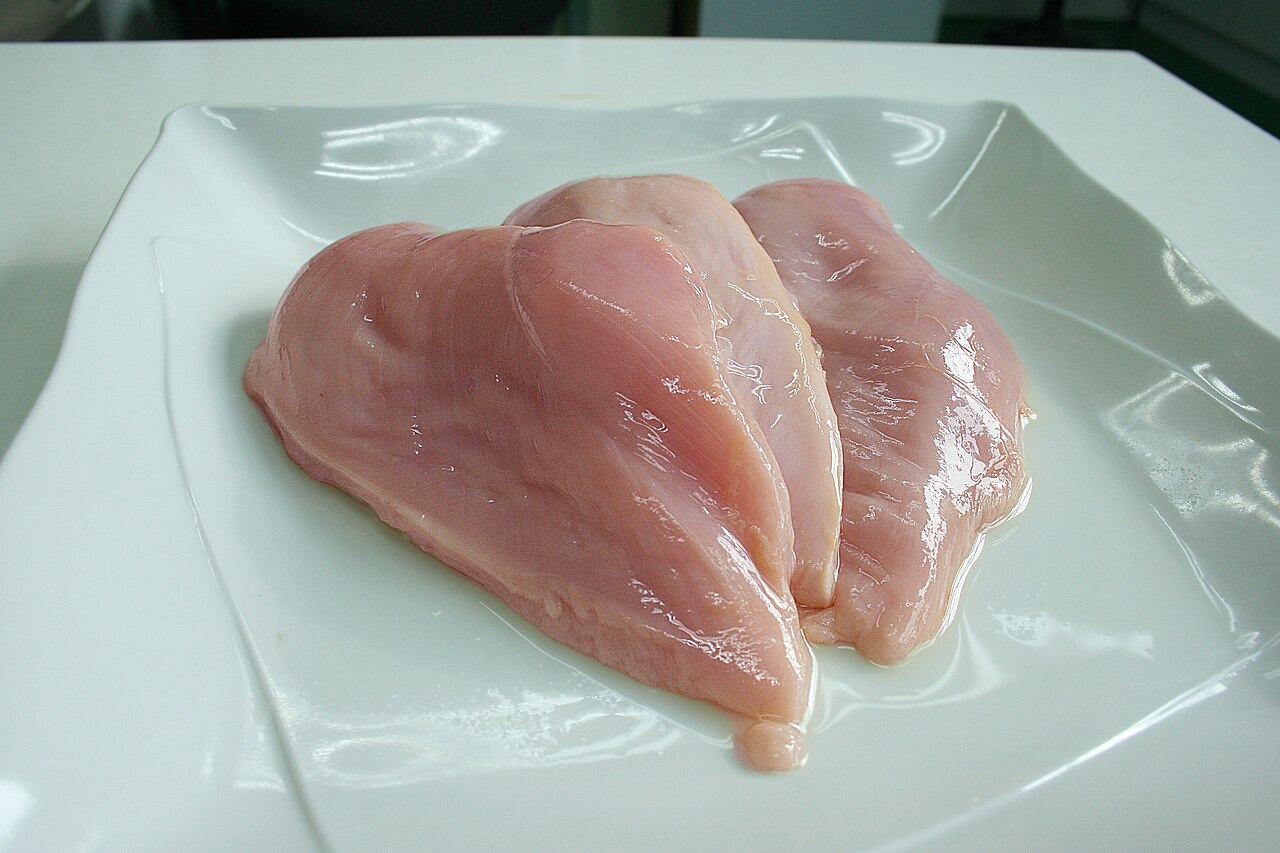 Filets de poulet crus sur une assiette blanche