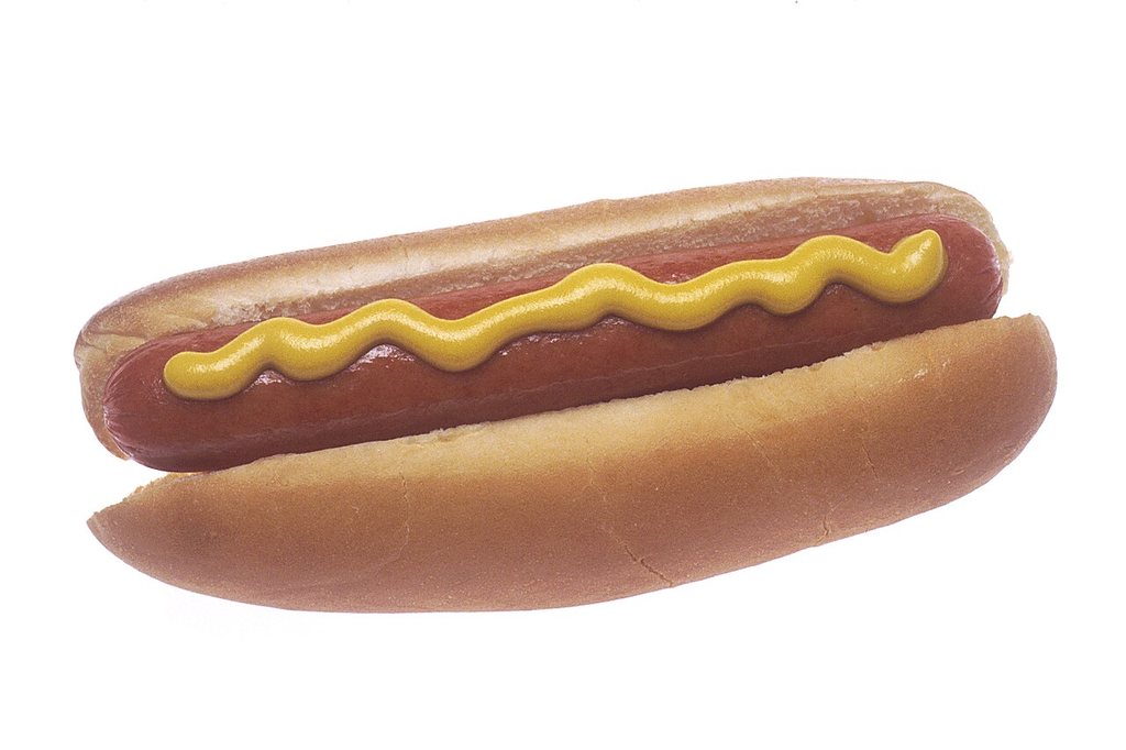 A hot dog in a bun with yellow mustard