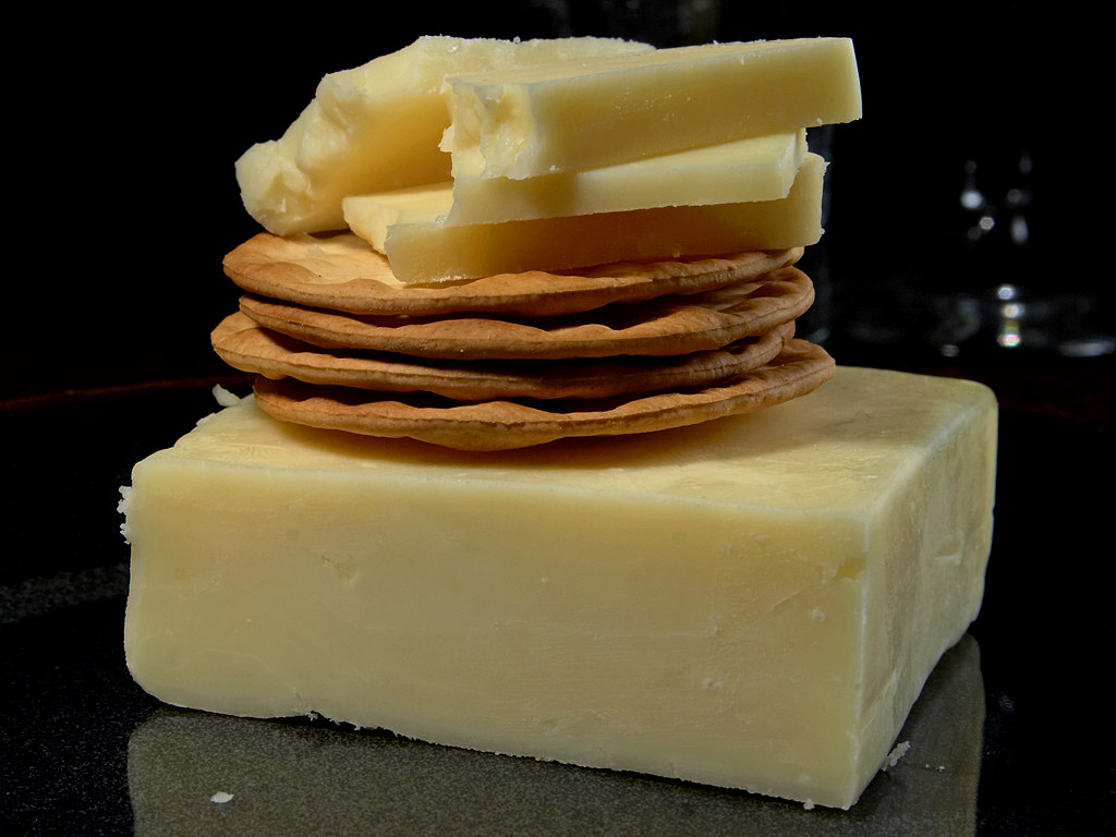 A block of white cheddar cheese with crackers